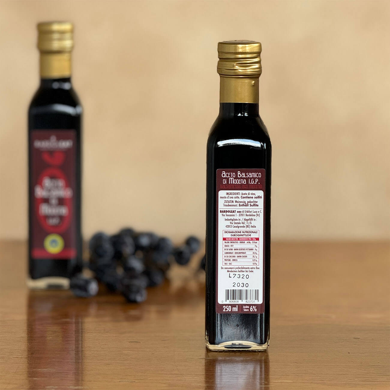 Flasche mit Aceto Balsamico di Modena steht auf einem Tisch. Zu sehen ist die Rückseite mit der Zutatenliste.