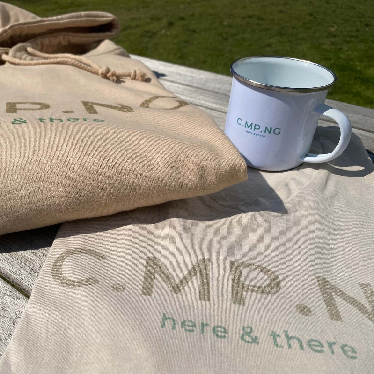 Camping-Hoodie und Camping T-Sirt in beige und Camping-Emaillebecher mit Aufdruck C.MP.NG here and there