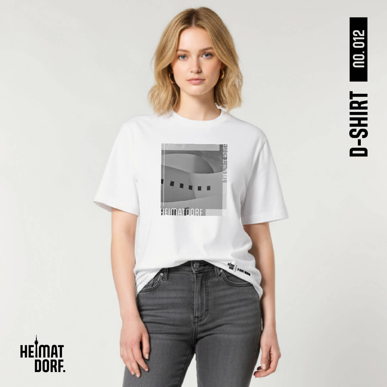 Junge Frau trägt weißes Düsseldorf T-Shirt zu einer grauen Jeans. Auf dem T-Shirt befindet sich in Graustufen ein Fotoausschnitt vom Düsseldorfer Schauspielhaus. Am unteren Rand ist der Begriff Heimatdorf in weiß aufgedruckt. Rechts oben ist ebenfalls in weiß "The white house" aufgedruckt. Das Düsseldorf T-Shirt ist die No. 012 der D-Shirt Kollektion.