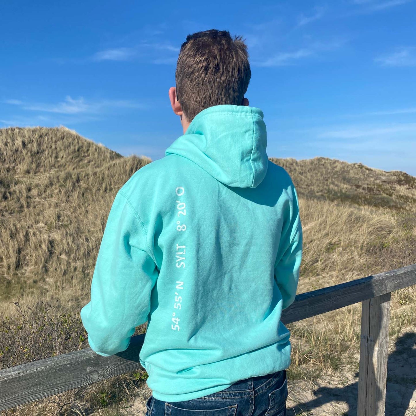 Sylt Hoodie in aqua-türkis mit senkrechtem Aufdruck Sylt und Koordinaten auf der linken Rückenseite