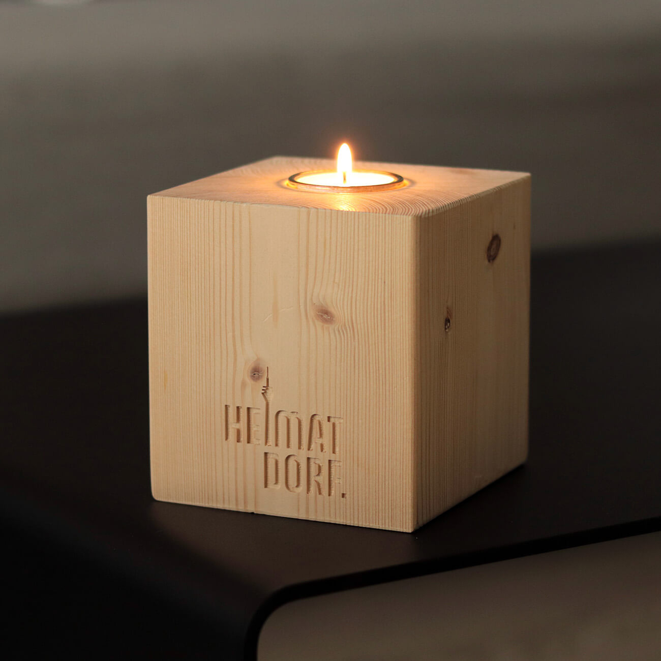 Düsseldorf Kerzenhalteraus Holz in Wrfelform mit Fräsung "HeimatDorf" auf der Vorderseite.