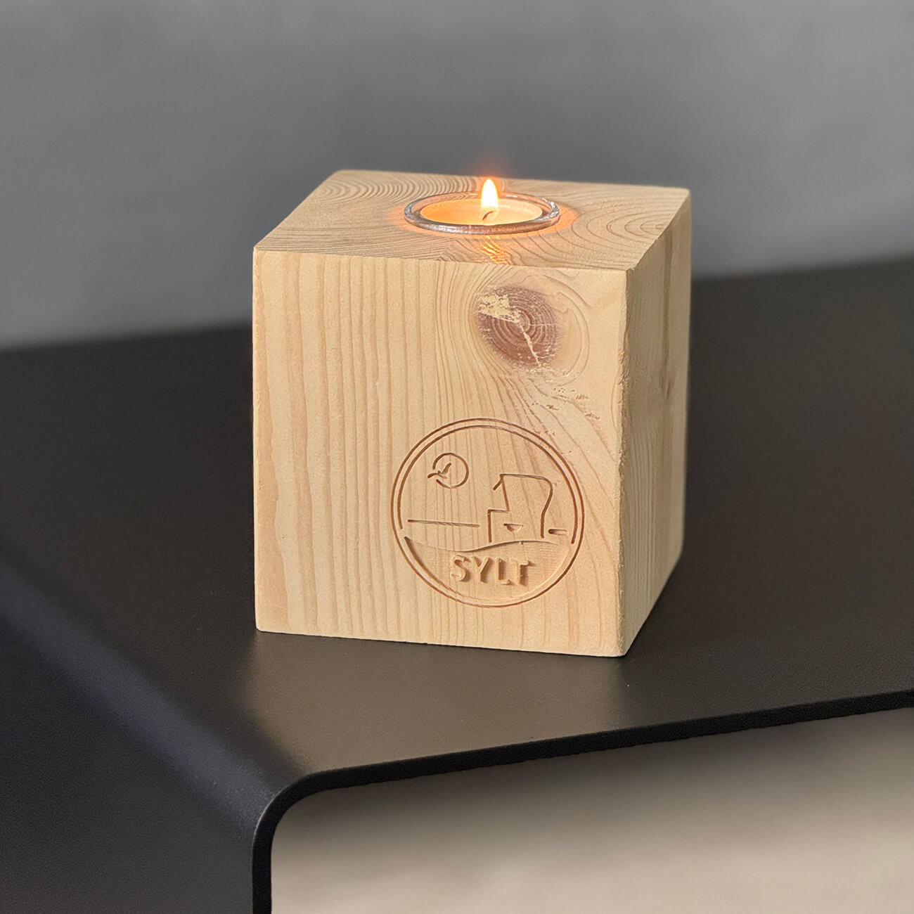 Sylt Kerzenständer in Würfelform aus Holz mit Glas-Einsatz für ein Teelicht. Mit Fräsung des Schriftzuges Sylt mit Strandkorb und vorbeifliegender Möwe in der Sonne.