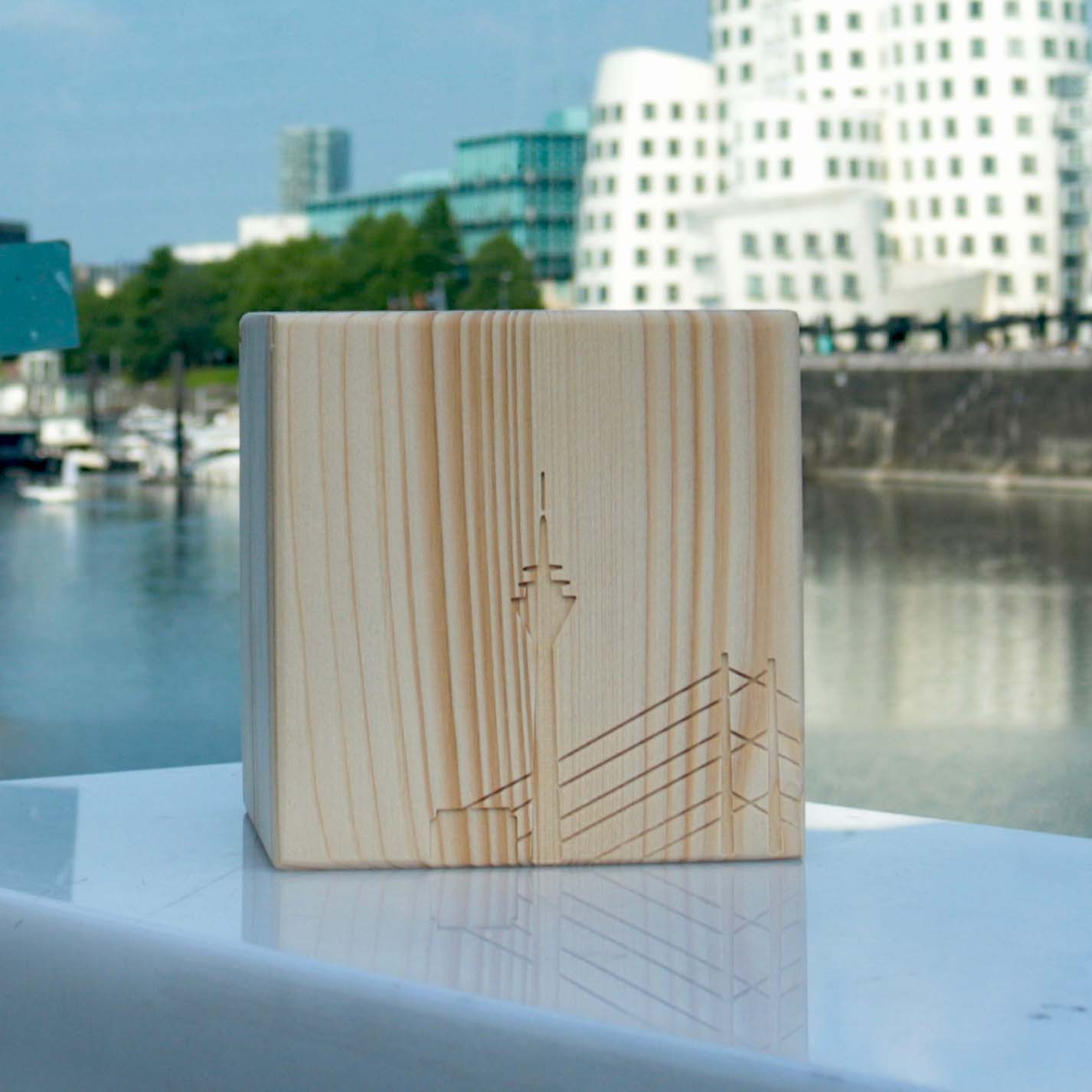 Teelicht Kerzenhalter aus massivem Holt und eingefasster Düsseldorf Skyline steht am MedienHafen mit Blick auf den Hafen und den Gehry Häusern im Anschnitt.