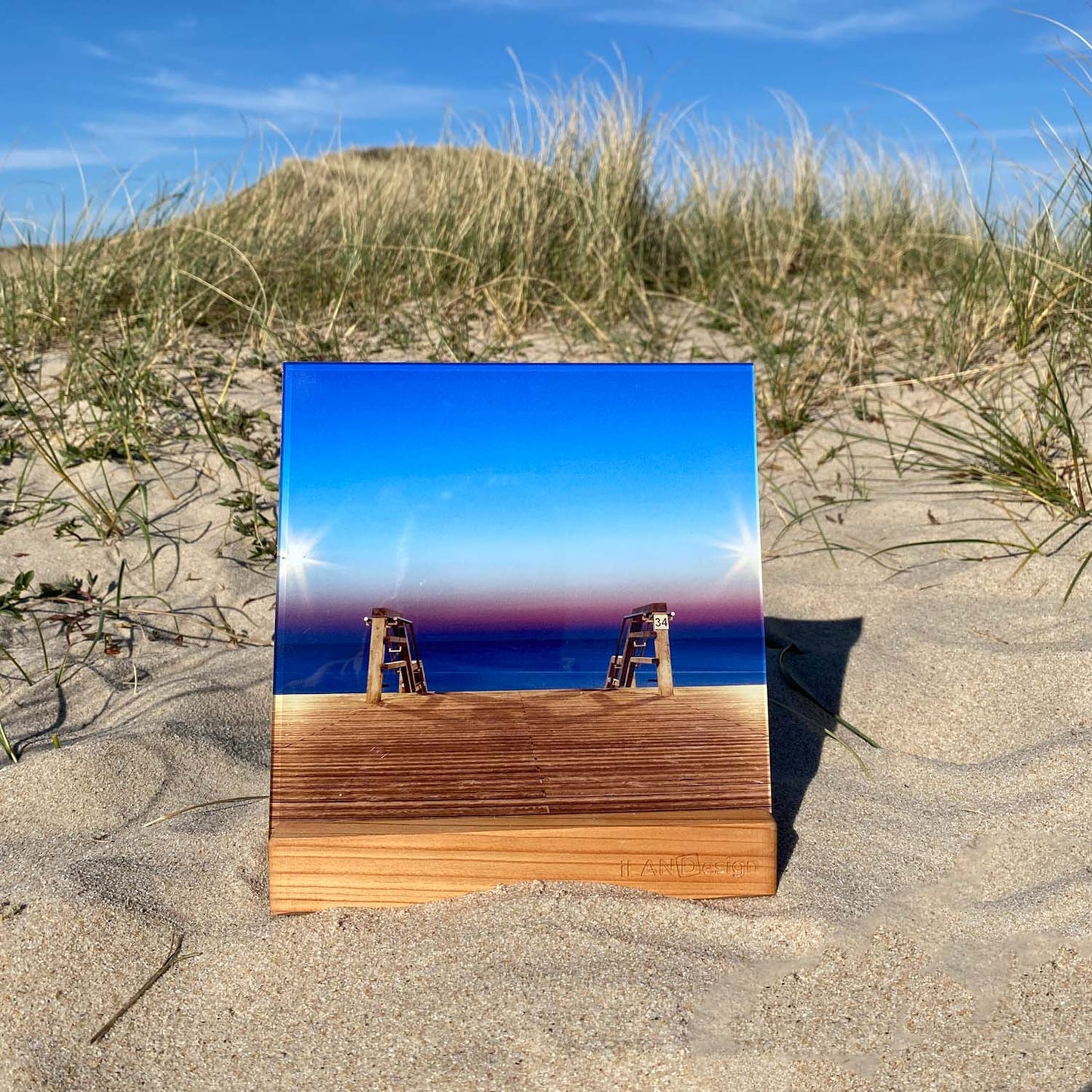 Acrylbild mit Wenningstedter Strandtreppe in der Abenddämmerung steht in einem Holzbilderhalter in den Sylter Dünen.