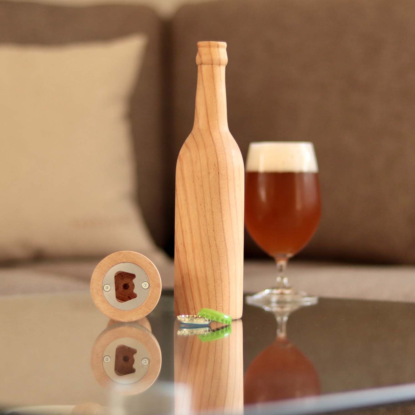 Longneck Flasche aus Holz steht auf einem Tisch. Eine weitere Holzflasche liegt, so dass der im Fuß eingearbeitete Flaschenöffner zu sehen ist.