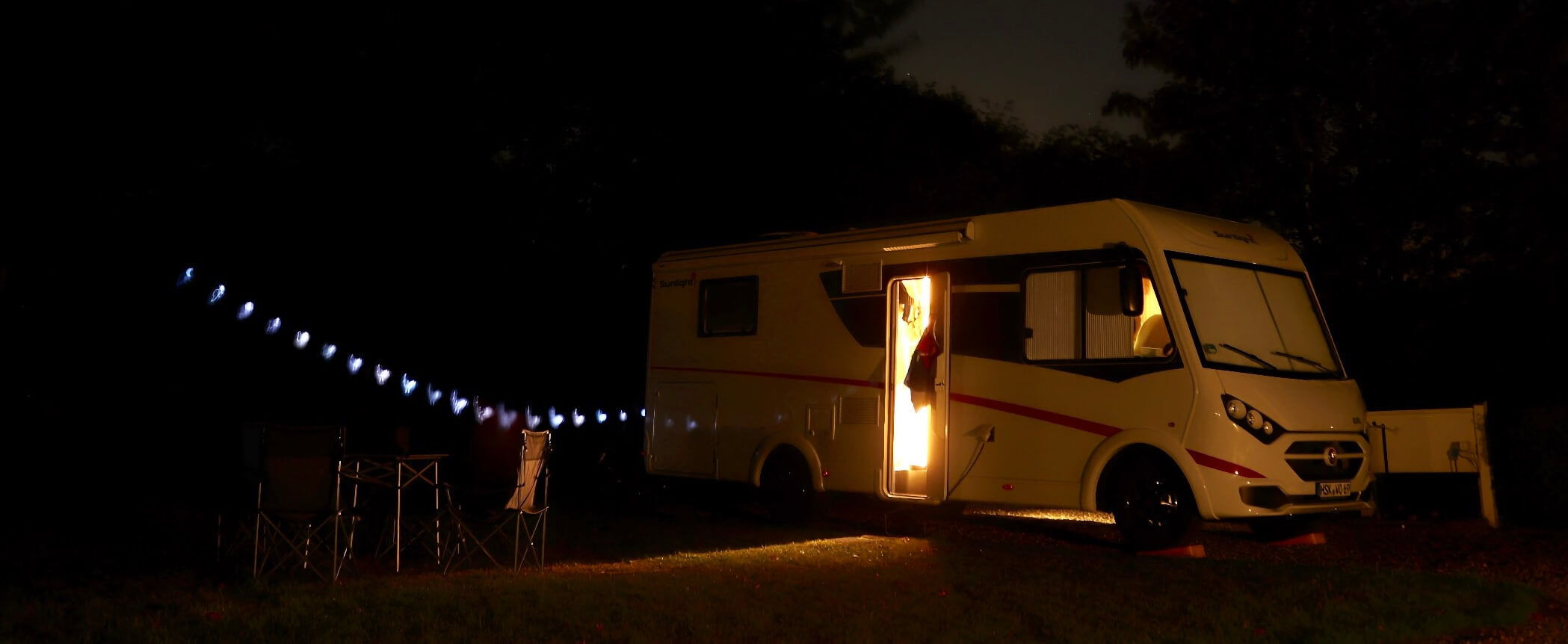 EIn Wohnmobil steht mit schöner Deko abends auf einem Campingplatz.