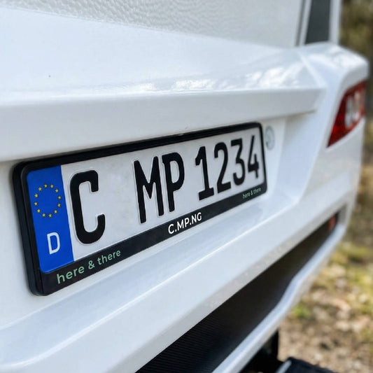 Nahaufnahme des Hecks eines Wohnmobils, der Fokus liegt auf dem C.MP.NG Kennzeichenhalter original mit dem Schriftzug C.MP.NG here & there