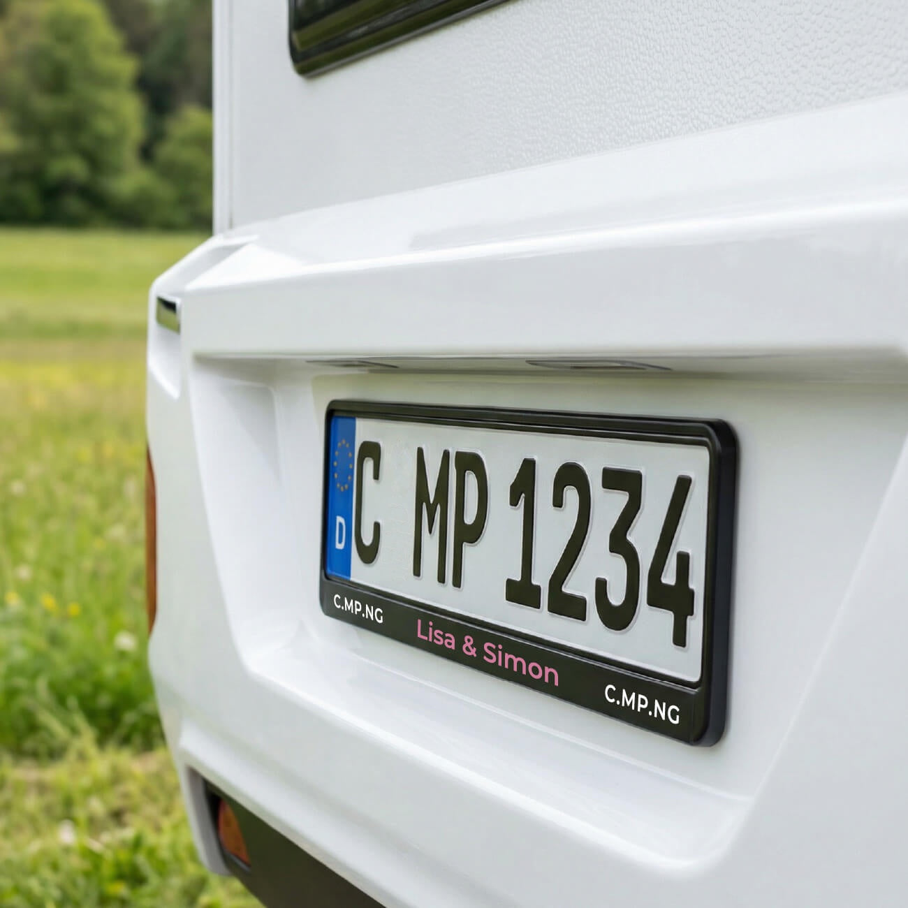 Das Heck eines Wohnwagens, im Fokus ist der personalisierte C.MP.NG Kennzeichenhalter 2.0.
In Rosa ist der Schriftzug Lisa & Simon zu sehen, rechts und links C.MP.NG