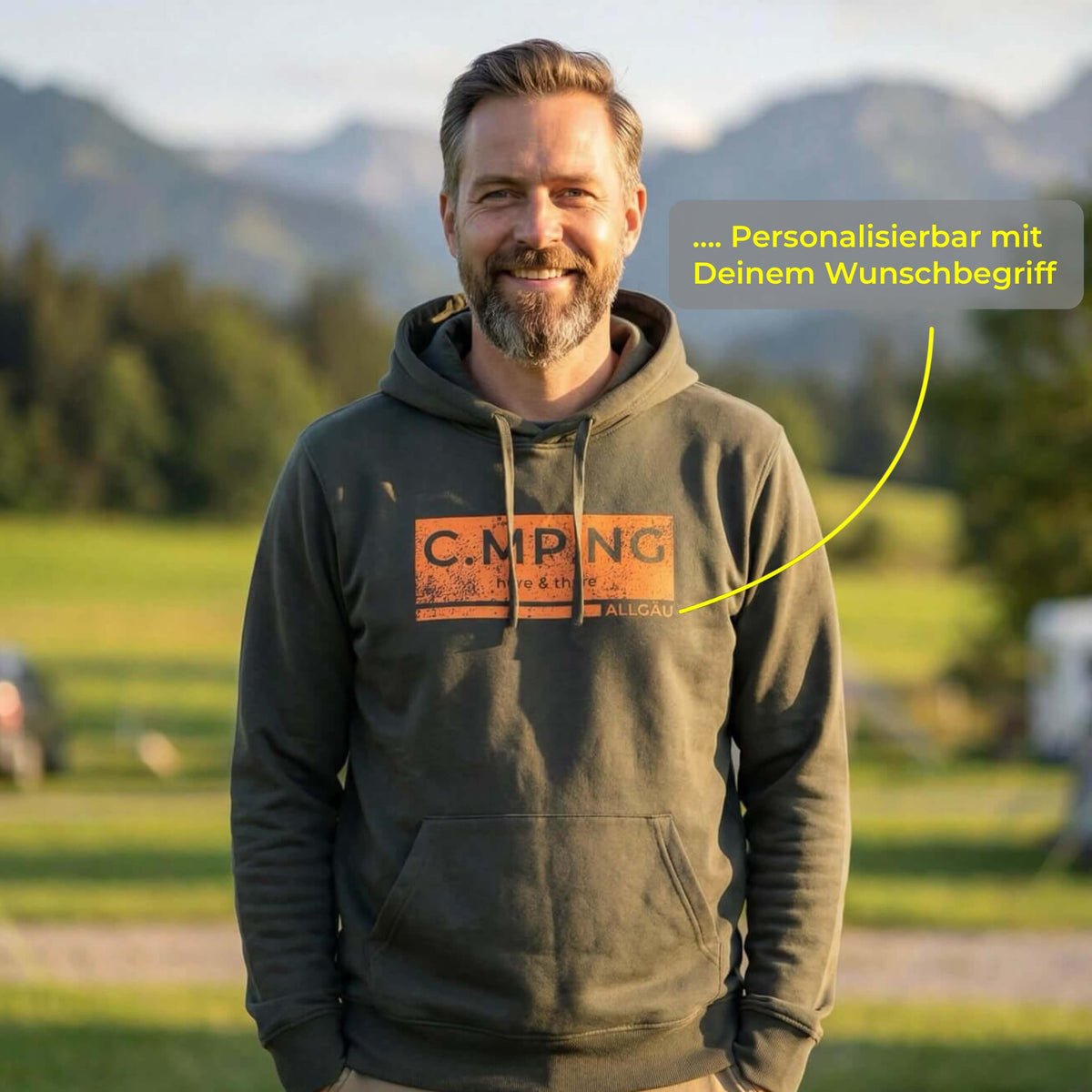 Ein mittelalter Mann steht vor einem bergischen Hintergrund mit einem dunkelgrünen Hoodie von C.MP.NG an