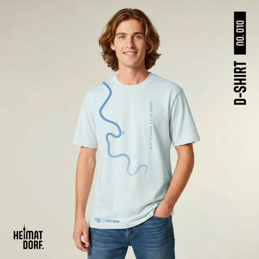 Junger Mann trägt ein Düsseldorf T-Shirt in light blue. Von der linken Schulter läuft der stilisierte Rheinverlauf bis über die Mitte des Shirts. Das Shirt kann mit den eigenen Heimatkoordinaten und einem Standortzeichen individualisiert werden. Das T-Shirt ist die No. 010 aus der Heimatdorf D-Shirt Kollektion – Das Düsseldorf-Shirt.