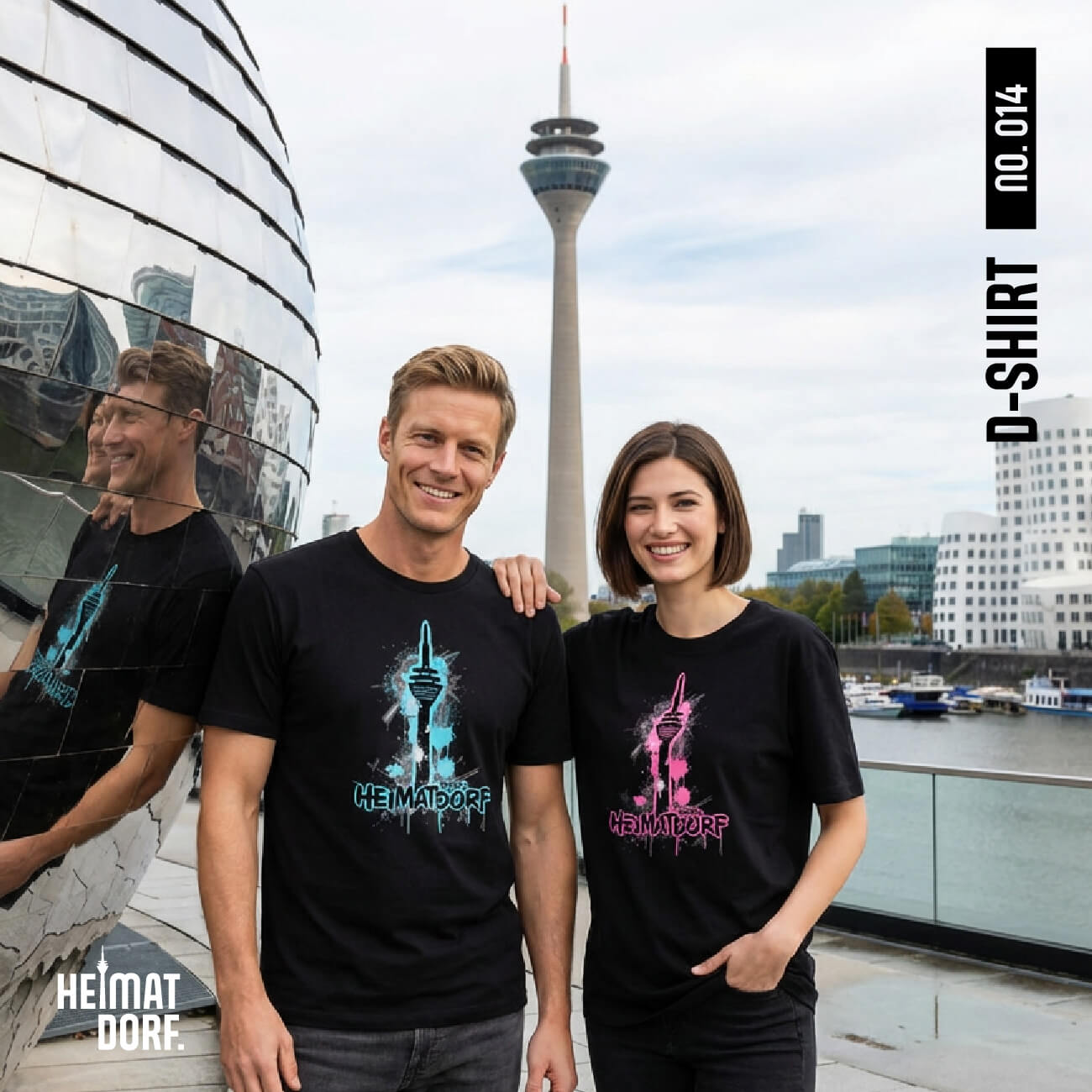 Mann und Frau mit schwarzen Düsseldorf T-Shirts im Medienhafen Düsseldorf. Im Hintergrund sieht man den Rheinturm und die Gehry Häuser.