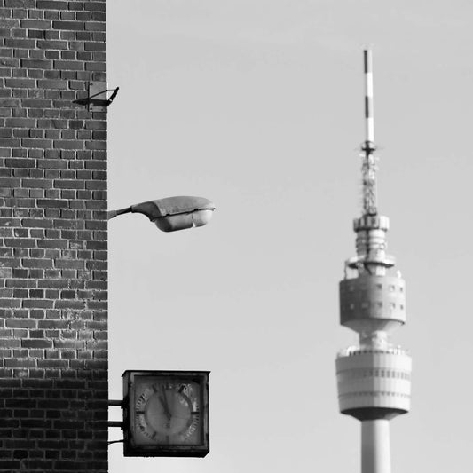 Schwarz-weiss Foto von einem Ausschnitt eines alten Brauerei-Gebäudes in Dortmund. Auf der rechten Seite sieht man den in der Ferne liegenden Florianturm.