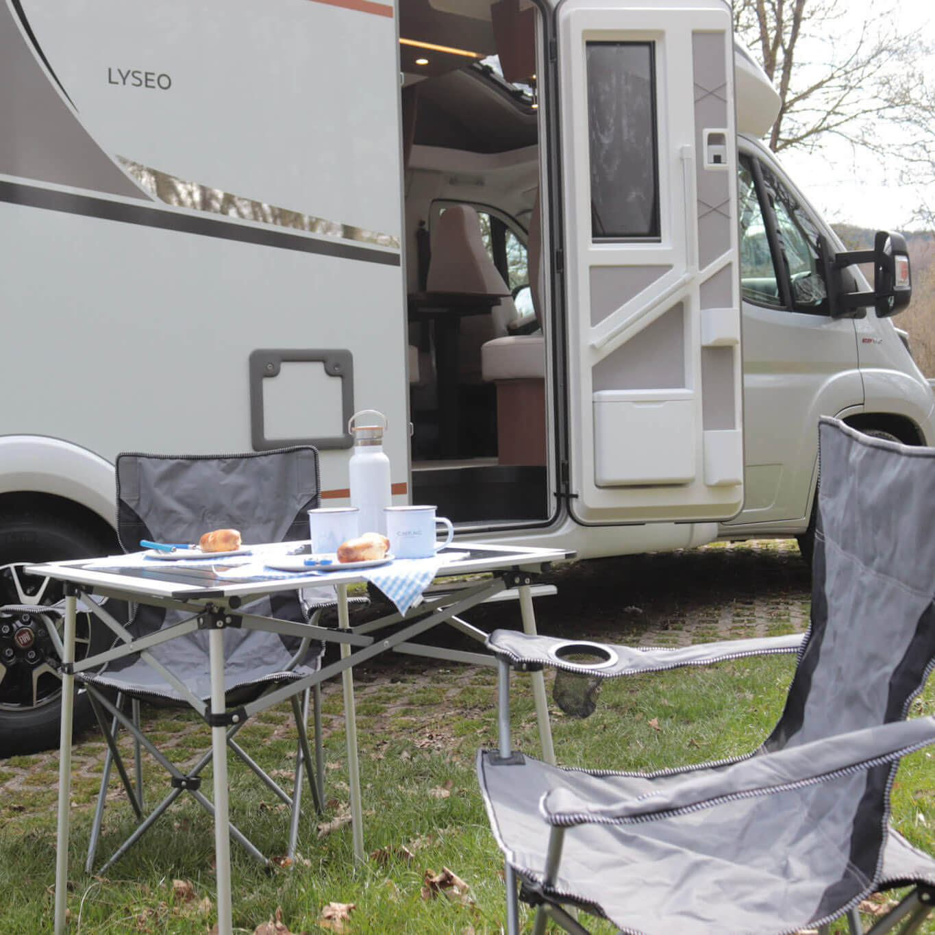 Ein Wohnmobil steht auf einem Stellplatz, davor ist ein gedeckter Campingtisch