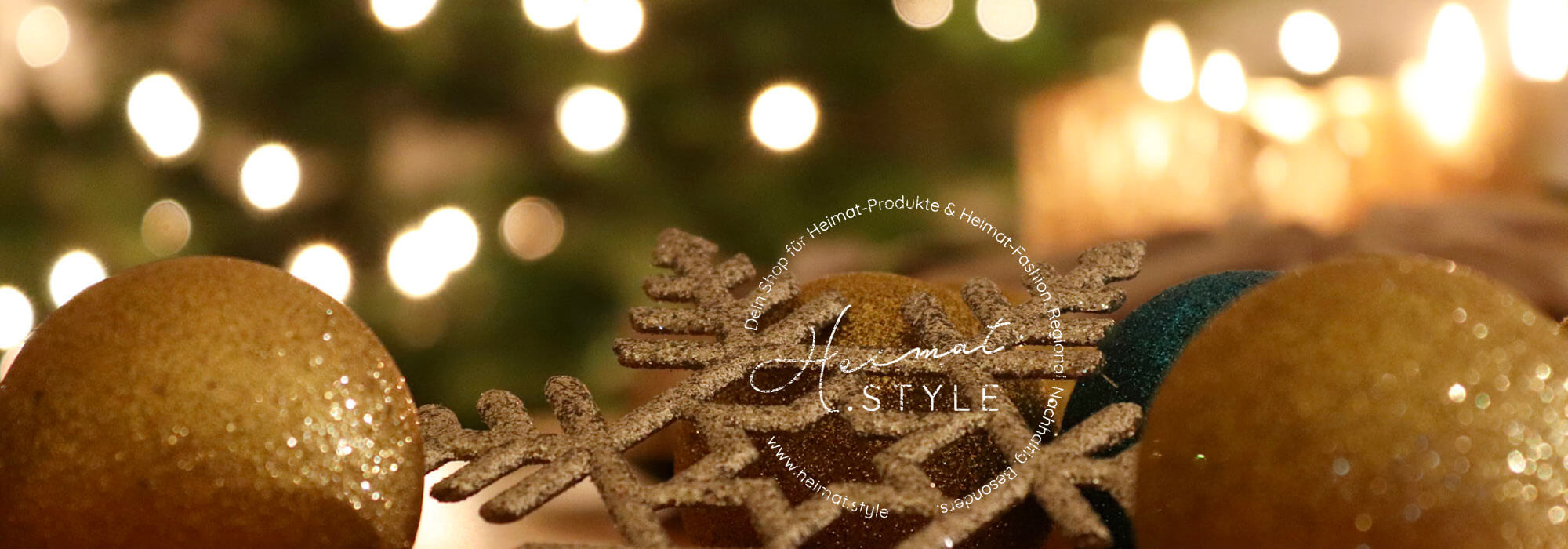 Heimat.Style Logo auf Foto mit Weihnachtsdekoration in gold und Lichtern im Hintergrund