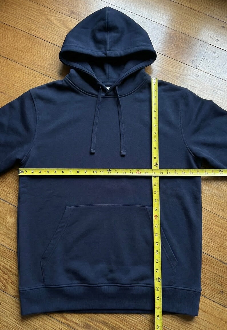 Ein Hoodie liegt ausgebreitet auf dem Boden, darauf 2 Maßbänder