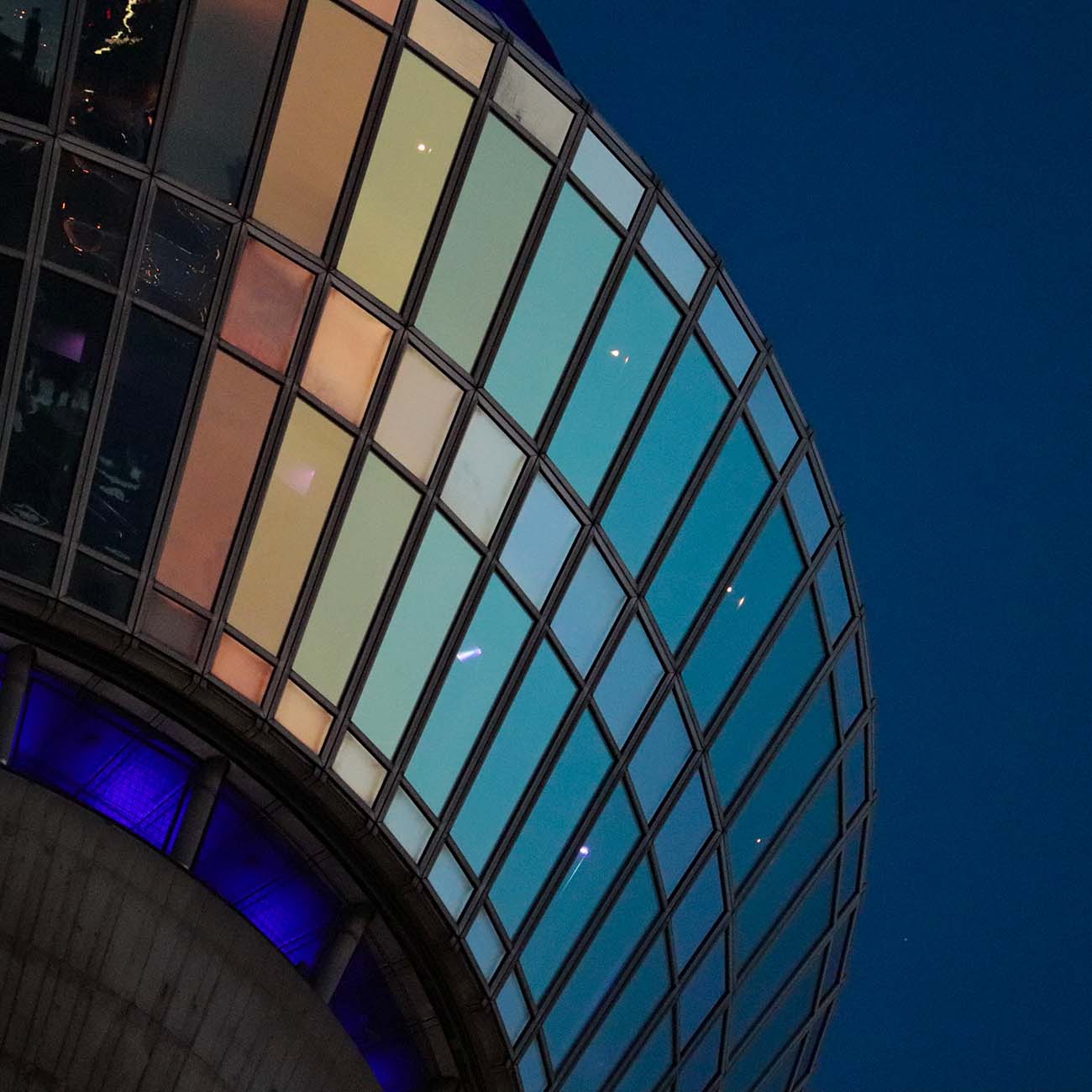 Auf dem Bild ist ein Ausschnitt des Düsseldorfer Rheinturms zu sehen. Die Scheiben sind in einem Farbverlauf von gold zu blau getaucht, da gerade der Übergang von goldener zu blauer Stunde stattfindet. Im Hintergrund sieht man den dunkelblauen Abendhimmel.