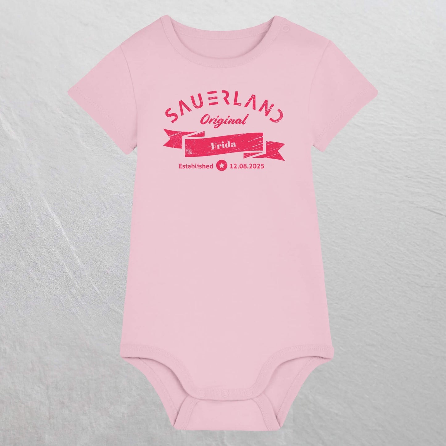 Rosa farbiger Baby-Body mit pinkfarbigem Aufdruck Sauerland Original, dem Vornamen und Geburtsdatum des Babys.