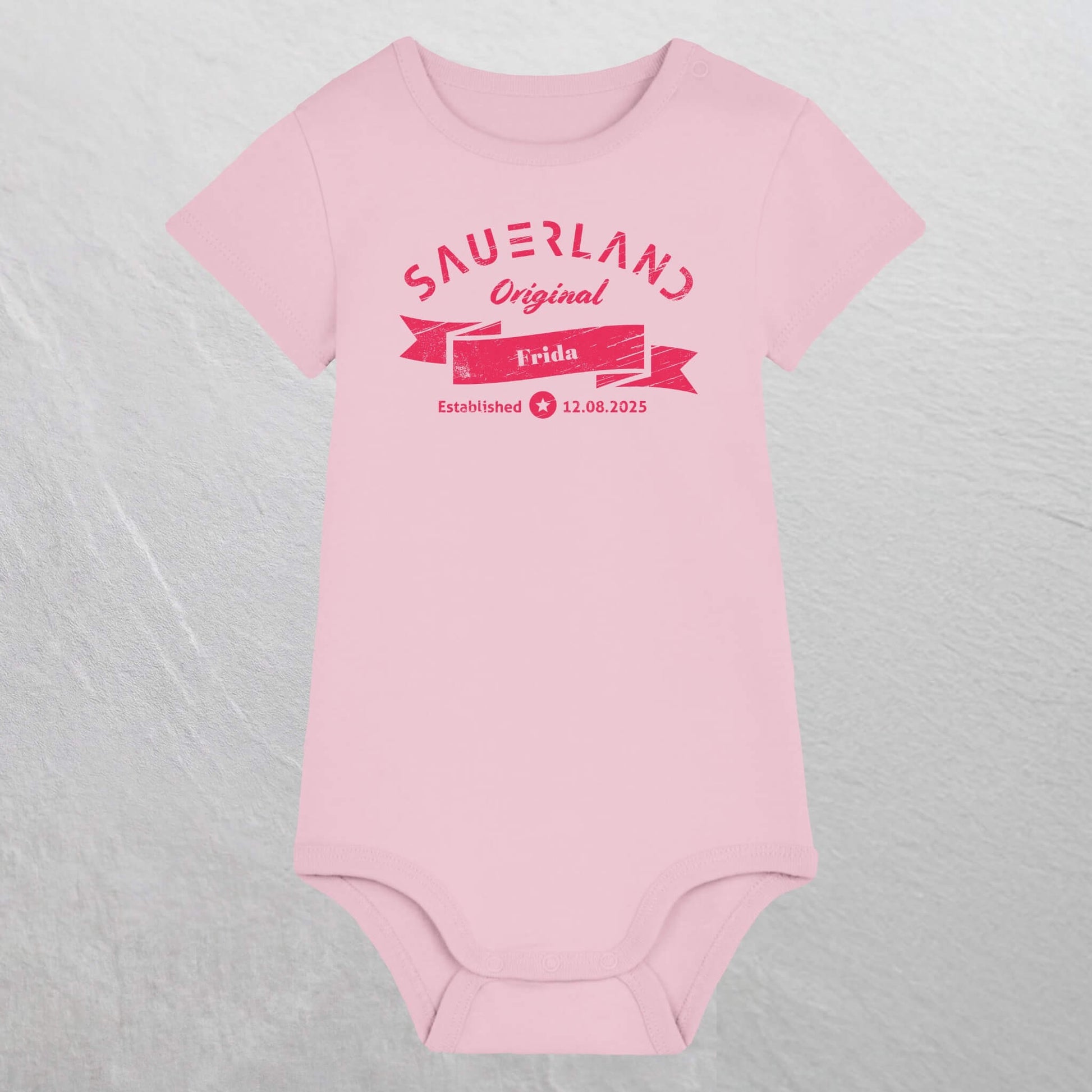 Rosa farbiger Baby-Body mit pinkfarbigem Aufdruck Sauerland Original, dem Vornamen und Geburtsdatum des Babys.