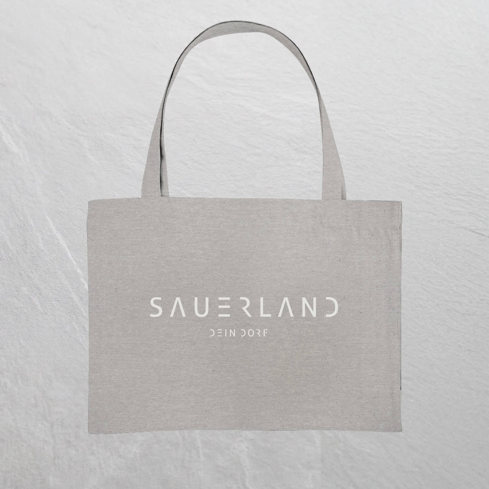 Graue Baumwolltasche mit weißem Sauerland Logo bedruckt. Der moderne Schriftzug wird darunter mit dem Dorfnamen ergänzt. 