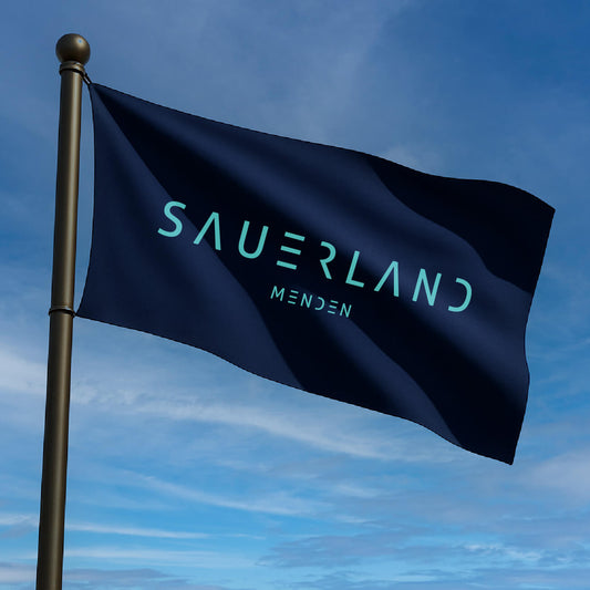 Sauerland Fahne in dunkelblau weht im Wind. In türkis ist das neue Sauerland Logo sowie die Stadt Menden aufgedruckt.