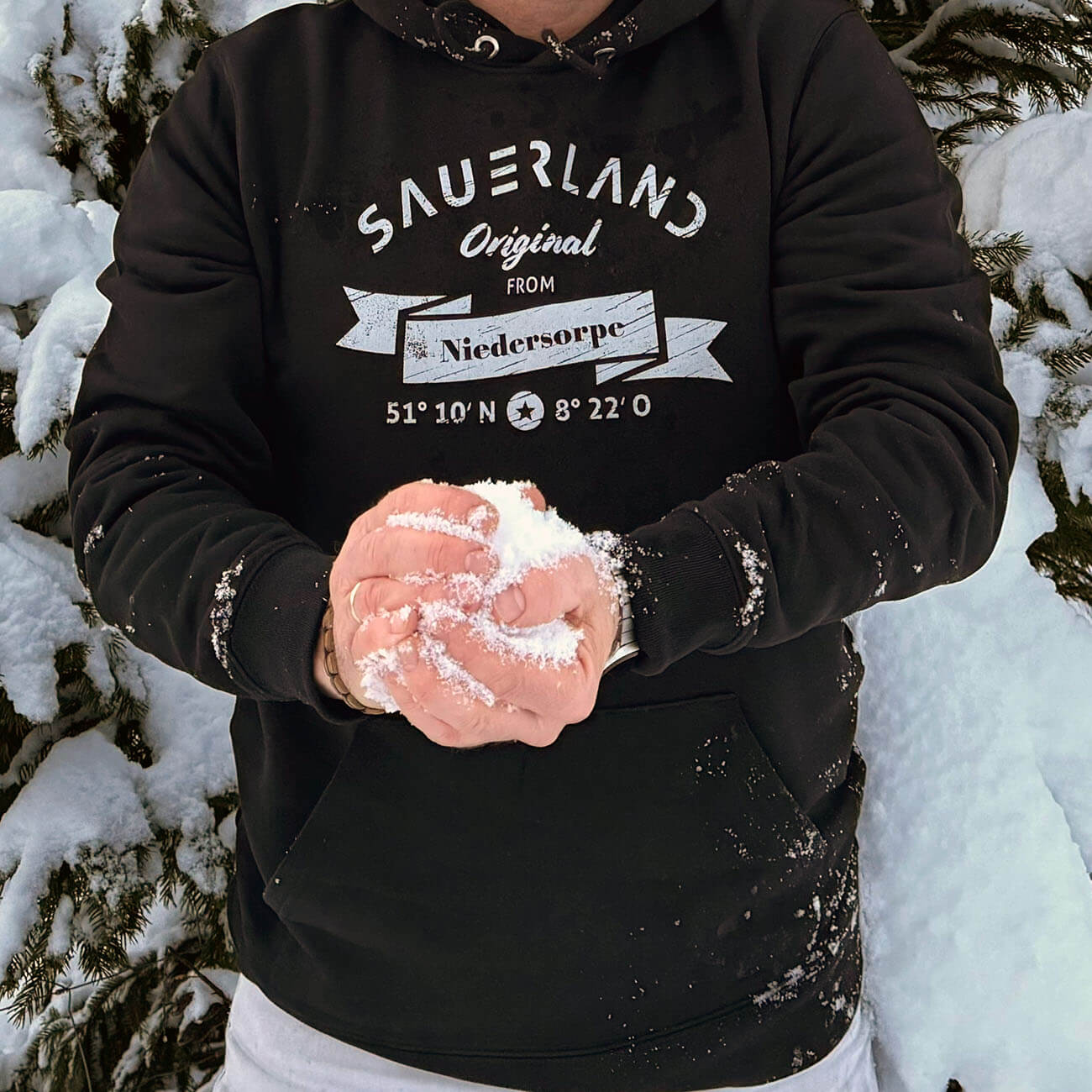 Mann im Schnee mit schwarzem Sauerland Hoodie mit hellgrauem Aufdruck Sauerland Original from Niedersorpe.