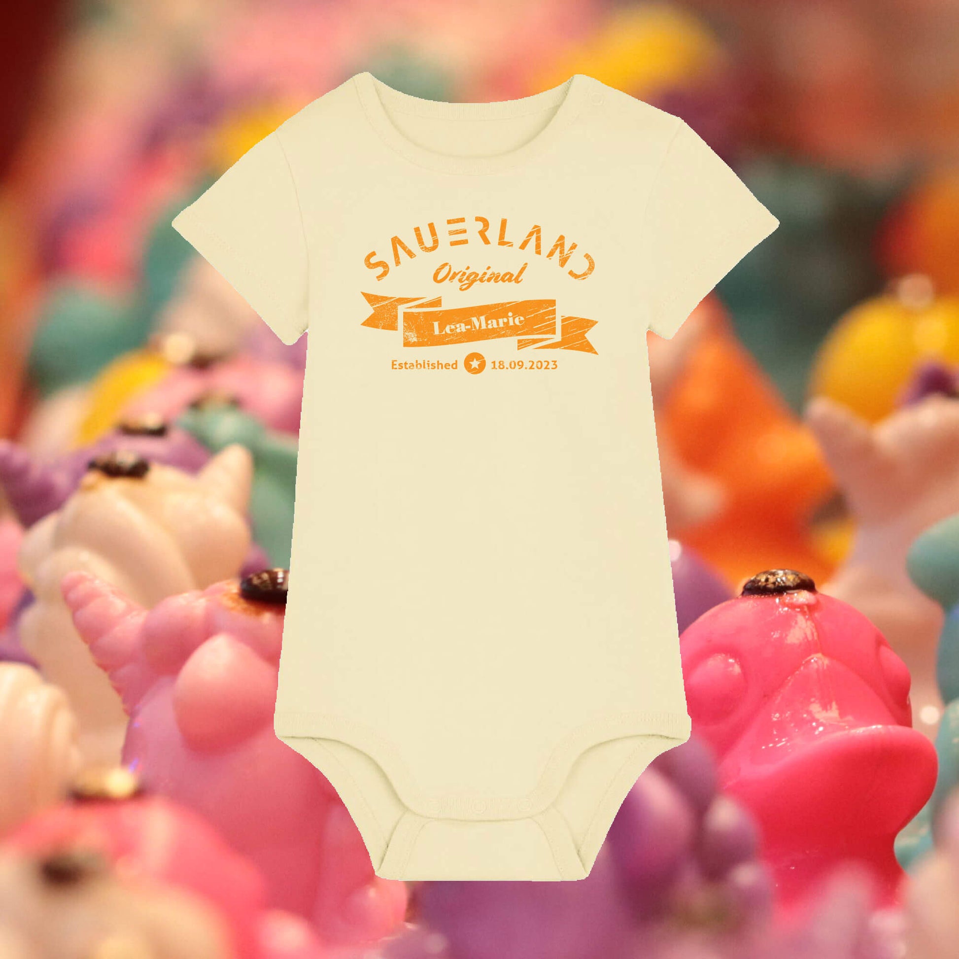 Blaßgelber Baby-Body für Babys aus dem Sauerland. Der Aufdruck ist orange und mit dem neuen Sauerland Logo sowie dem Babynamen und dem Geburtsdatum individualisierbar.