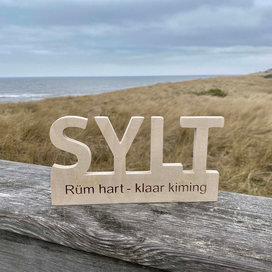 Holz Deko-Schild mit dem Begriff Sylt Rüm hart klar kiming steht am Strandausfgang mit Blick in die Dünen und aufs Meer.