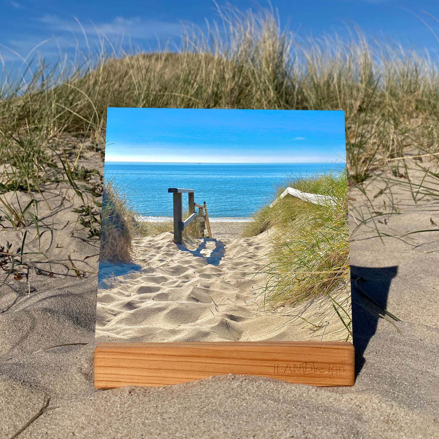 Acrylbild mit Strandtreppe zum Meer. Rechts und links sieht man Dünengras und einen wunderschönen Blick auf die Nordsee. Das Foto wurde auf der Insel Sylt gemacht. Das Acrylbild steht in einem Holzaufsteller in den Sylter Dünen.