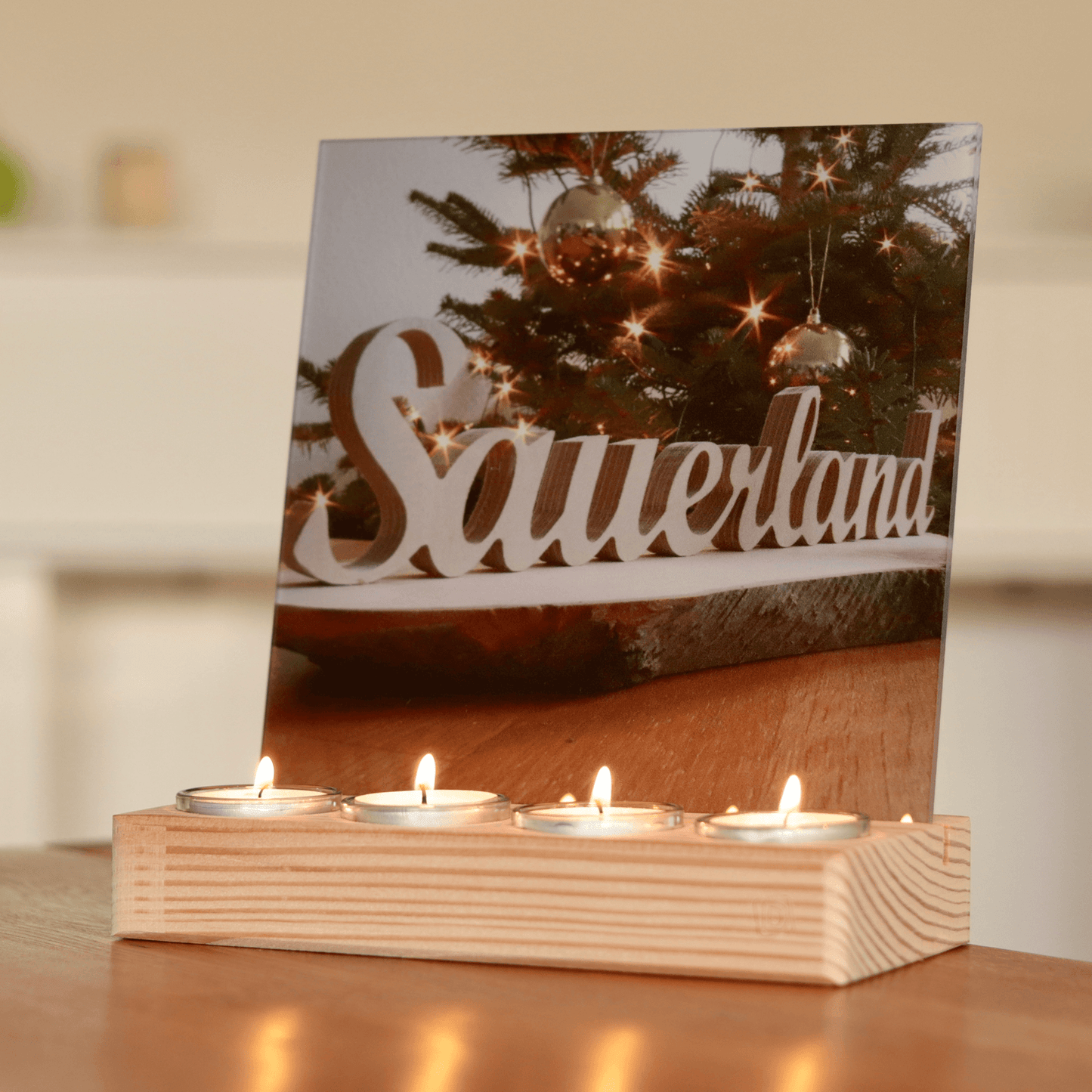 Holz-Bilderhalter aus Fichtenholz. Vorne sind vier Teelichte eingesetzt. Dahinter befindet sich ein Schlitz, in den eine Acrylglasplatte im Format 20 x 20 cm eingesetzt ist. Auf der Acrylplatte ist ein weihnachtliches Sauerland-Motiv zu sehen.