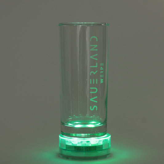 Ein Sauerland Trinkglas steht auf einer grünen, runden Lampe. Hierdurch ist die Gravur mit dem modernen Sauerland Logo und darunter, etwas kleiner, dem Dorfnamen Werpe zu sehen. 