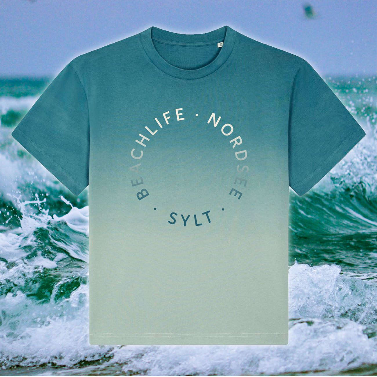 T-Shirt mit Farbverlauf und Sylt-Aufdruck. Das Shirt ist am Rundhalsausschnitt in einem grün-blau gefärbt und läuft in ein beige aus. In der gleichen, aber umgekehrten Farbe steht in rund der Schriftzug Beachlife, Nordsee, Sylt. Im Hintergrund sieht man einen Detailausschnitt der Nordsee-Wellen. 